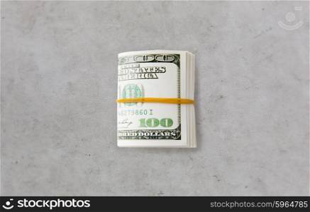 business, finance, investment, saving and corruption concept - close up of dollar money packet tied with rubber on gray concrete table