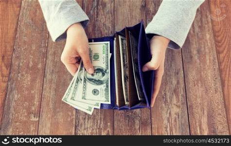 business, finance, saving, banking and people concept - close up of woman hands with wallet and us dollar money on wooden table