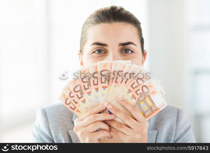 business, finance, saving, banking and people concept - close up of woman hiding her face behind euro money fan