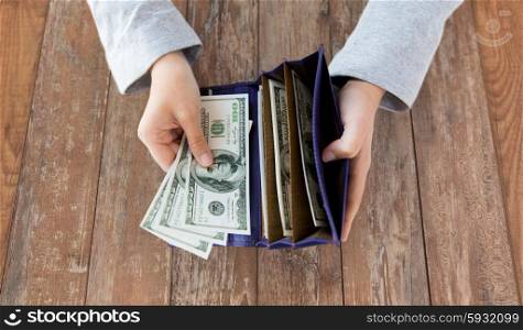 business, finance, saving, banking and people concept - close up of woman hands with wallet and us dollar money on wooden table