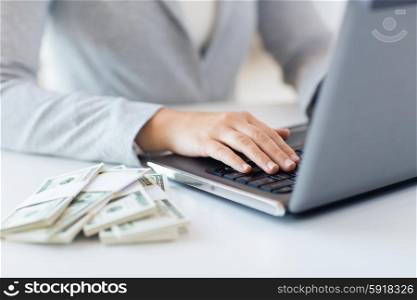business, finance, saving, technology and people concept - close up of woman hands with laptop computer and us dollar money