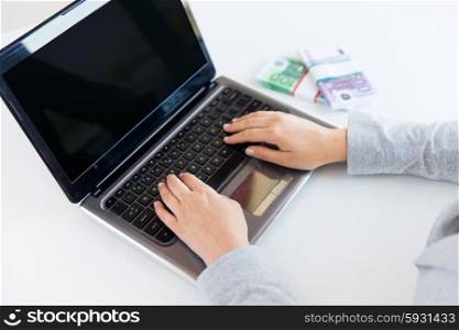 business, finance, saving, technology and people concept - close up of woman hands with laptop computer and euro money