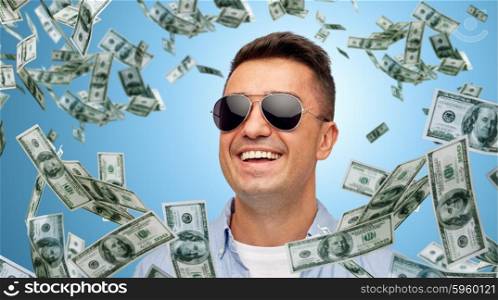 business, finance, success and people concept - face of smiling middle aged latin man in shirt and sunglasses over blue background with heap of falling dollar money