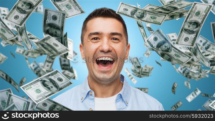 business, finance, success, emotions and people concept - laughing man over blue background with heap of falling dollar money