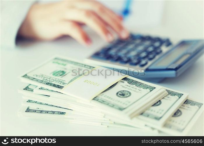 business, finance, tax and people concept - close up of woman hand counting us dollar money with calculator