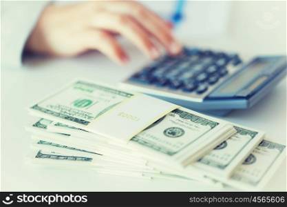 business, finance, tax and people concept - close up of woman hand counting us dollar money with calculator