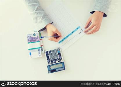 business, finance, tax and people concept - close up of woman hands counting euro money with calculator and tax report form