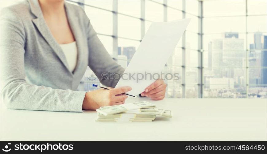business, finance, tax and people concept - close up of woman hands with us dollar money and tax report paper form over city office room background