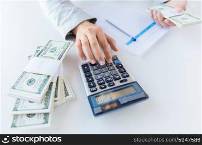 business, finance, tax and people concept - close up of woman hands counting us dollar money with calculator