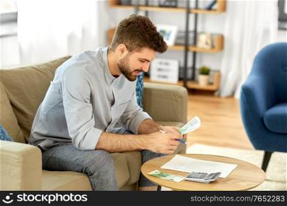 business, finances, accounting and people concept - man with money and calculator filling papers at home. man with money and calculator filling papers