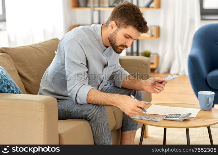 business, finances, accounting and people concept - man with money and calculator filling papers at home. man with money and calculator filling papers