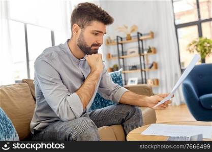 business, finances, accounting and people concept - stressed man with calculator counting and filling papers at home. stressed man with bills at home