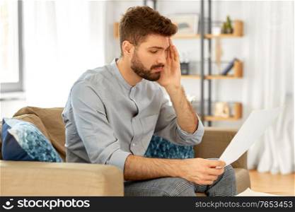 business, finances, accounting and people concept - unhappy man with bills or tax report at home. unhappy man with bills or tax report at home
