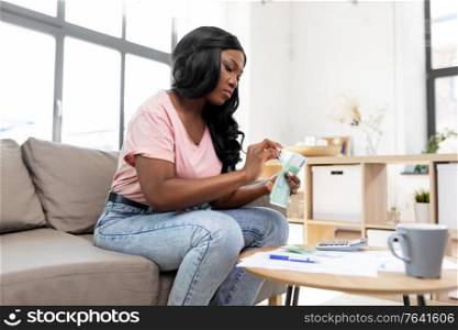 business, finances, income and people concept - african american woman counting money at home. african american woman counting money at home