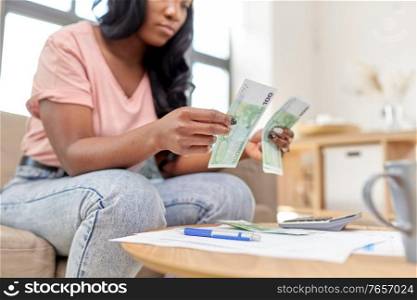 business, finances, income and people concept - african american woman counting money at home. african american woman counting money at home