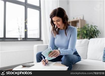 business, finances, income and people concept - happy smiling woman with calculator and bills counting money at home. happy woman counting money at home