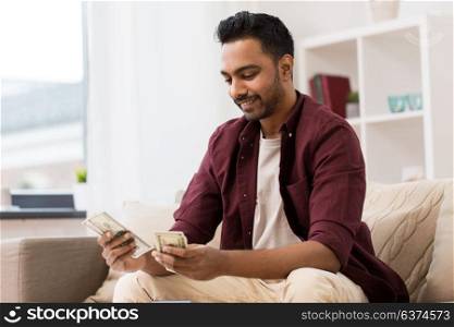 business, finances, income and people concept - smiling man counting money at home. smiling man counting money at home