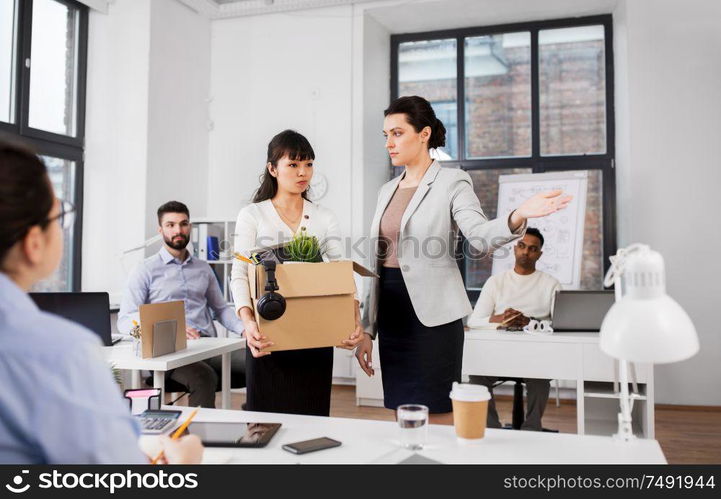 business, firing and job loss concept - executive and sad fired asian female office worker holding box of his personal stuff. executive seeing off fired female office worker