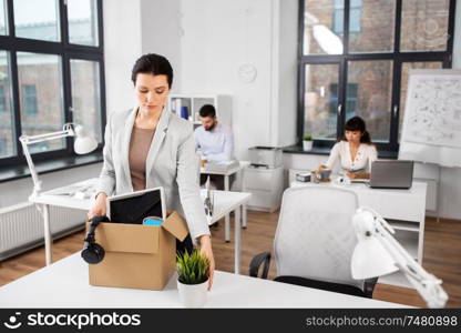business, firing and job loss concept - sad fired female office worker with box of her personal stuff. female office worker with box of personal stuff