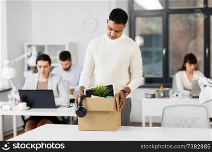 business, firing and job loss concept - sad fired indian male office worker with box of his personal stuff. sad fired male office worker with personal stuff