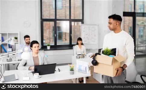 business, firing and job loss concept - sad fired indian male office worker with box of his personal stuff. sad fired male office worker with personal stuff