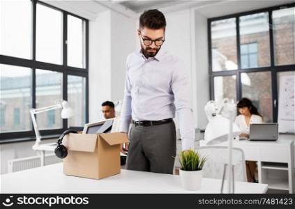 business, firing and job loss concept - sad fired male office worker with box of his personal stuff. sad fired male office worker with personal stuff