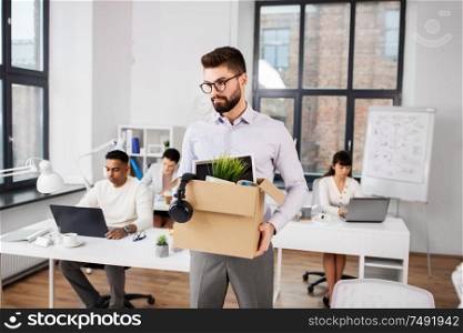 business, firing and job loss concept - sad fired male office worker with box of his personal stuff. sad fired male office worker with personal stuff