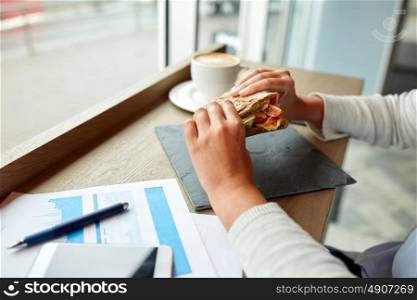 business, food and people concept - woman with papers eating salmon panini sandwich at cafe for dinner or lunch. woman eating salmon panini sandwich at cafe