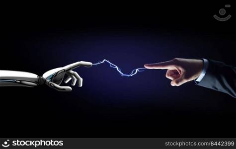 business, future technology and artificial intelligence concept - robot and human hand connected by lightning over black background. robot and human hand connected by lightning