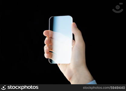 business, future technology and people concept - close up of male hand holding and showing transparent smartphone over black background