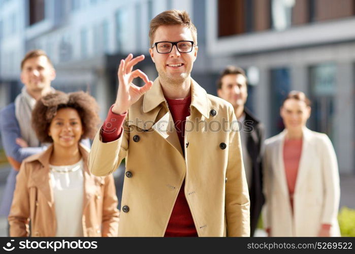 business, gesture and corporate concept - happy smiling man with international group of people showing ok hand sign outdoors. happy smiling man showing ok hand sign outdoors