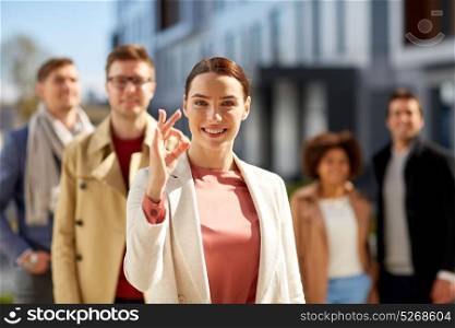 business, gesture and corporate concept - happy smiling woman with international group of people showing ok hand sign outdoors. happy smiling woman showing ok hand sign outdoors