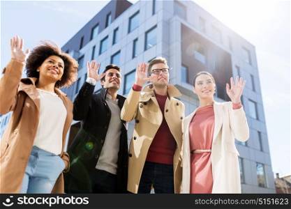 business, gesture and corporate concept - international group of people waving hands on city street. international group of people on city street