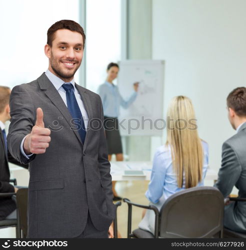 business, gesture and office concept - handsome buisnessman showing thumbs up in office