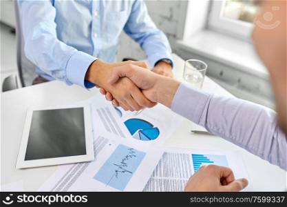 business, gesture and partnership concept - close up of businessmen making handshake at office. close up of businessmen making handshake at office
