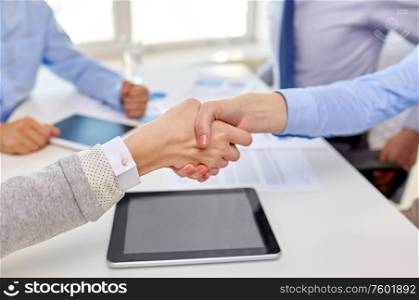 business, gesture and partnership concept - close up of businesspeople making handshake at office. close up of businesspeople making handshake