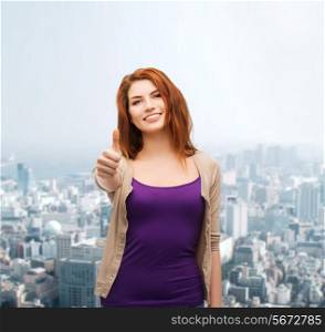 business, gesture and people concept - smiling teenage girl in casual clothes showing thumbs up over city background