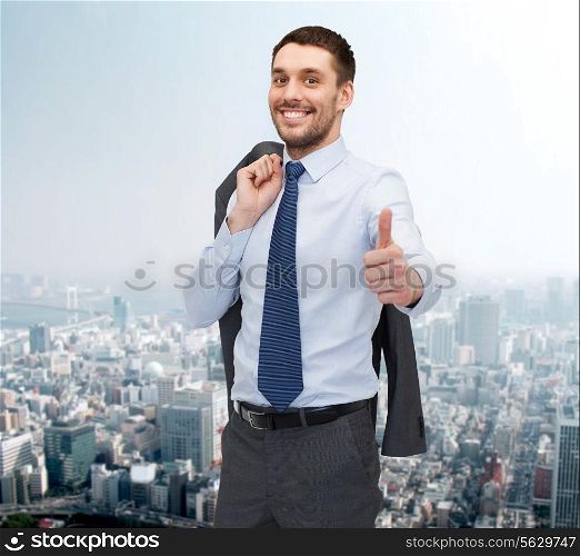 business, gesture and people concept - smiling young and handsome businessman showing thumbs up over cityscape background
