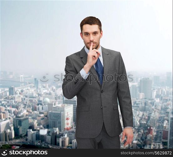 business, gesture and people concept - young businessman making hush sign over city background over cityscape background