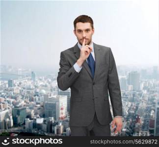 business, gesture and people concept - young businessman making hush sign over city background over cityscape background