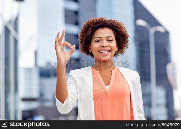 business, gesture and people concept - young smiling african american businesswoman showing ok hand sign in city