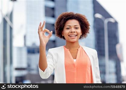 business, gesture and people concept - young smiling african american businesswoman showing ok hand sign in city