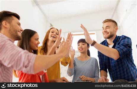 business, gesture, people and teamwork concept - happy creative team making high five at office. happy creative team making high five at office