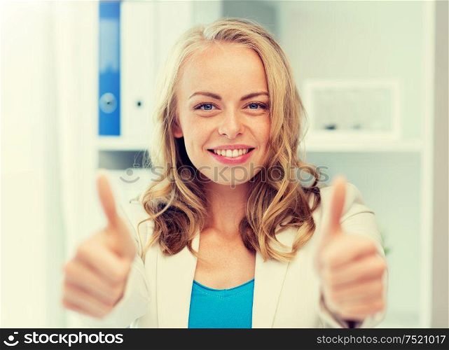 business, gesture, success, startup and people concept - happy businesswoman showing thumbs up at office. happy businesswoman showing thumbs up at office