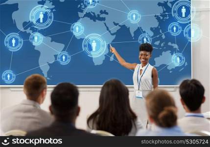 business, global network and people concept - smiling african american businesswoman or lecturer with world map on projection screen to group of students at conference presentation or lecture. group of people at business conference or lecture