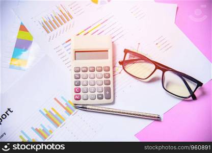Business graph chart report paper financial document with calculator pen and glasses on pink background