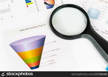 Business graph printed on the white paper with a magnifier on it