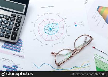 Business graph printed on white paper with calculator and glasses