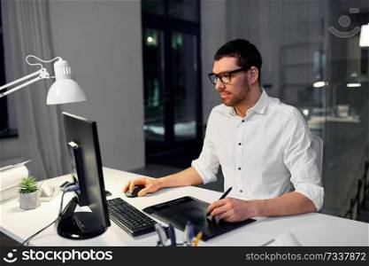 business, graphic design and technology concept - designer or businessman in glasses with computer and pen tablet working at dark night office. designer with computer and pen tablet at office