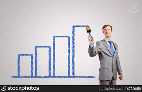 Business growth. Handsome businessman with paint brush in hand